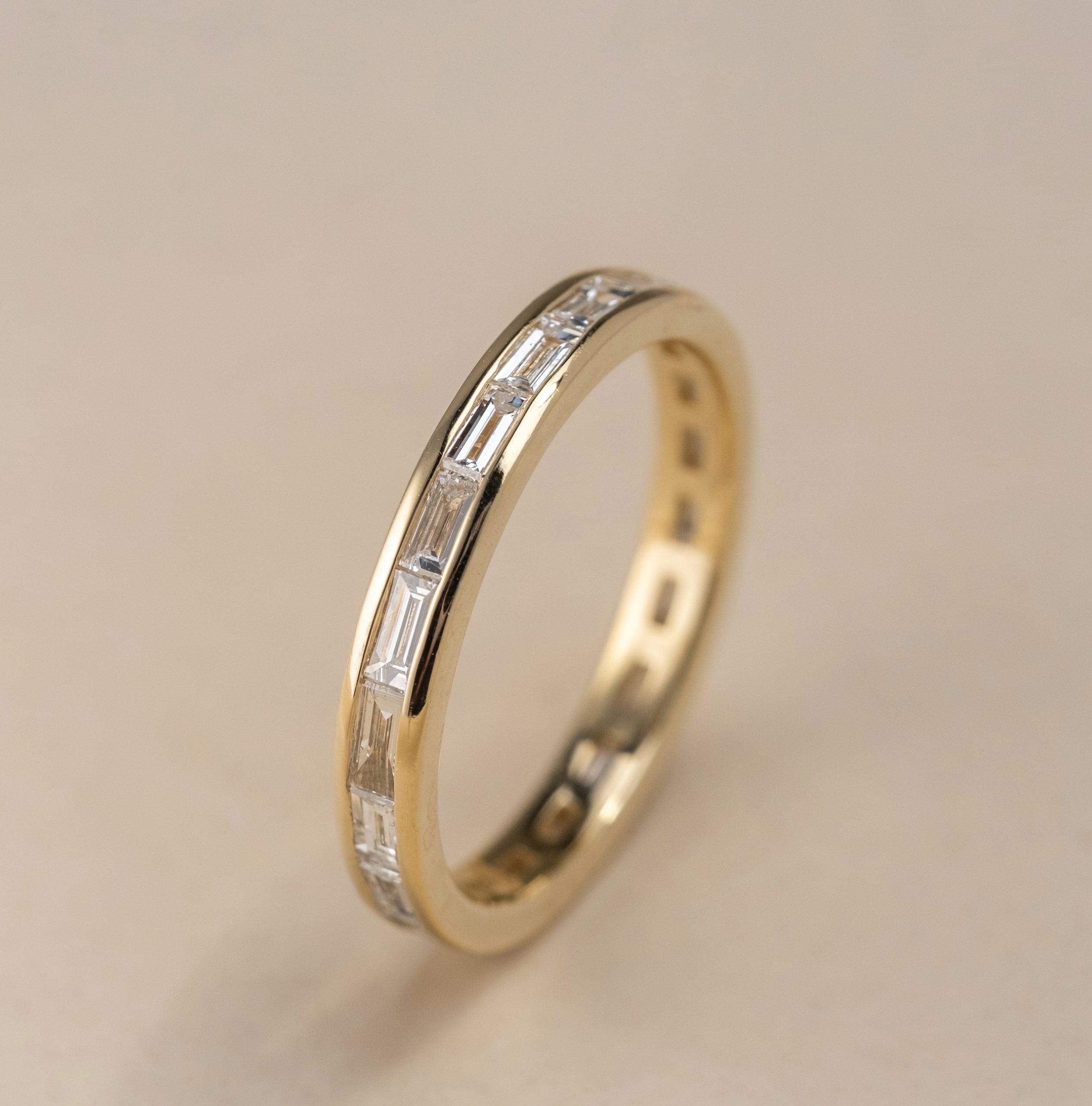 Vertical view of a channel set baguette diamond wedding band in 14k yellow gold