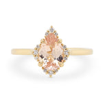 Peach colored pear shaped sapphire engagement ring with a 14k yellow gold diamond halo setting