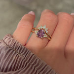 Video of a hand modeling a 14k yellow gold pink sapphire engagement ring and diamond wedding band