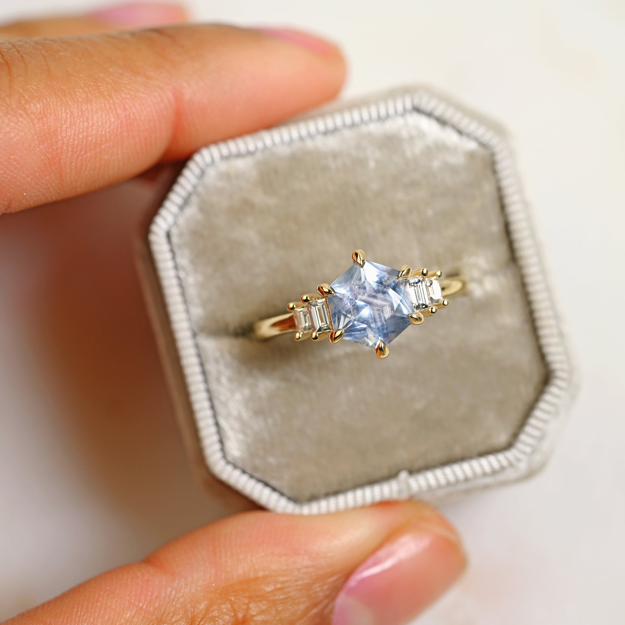 Light blue Montana hexagon sapphire engagement ring with baguette diamonds set in 14k yellow gold in a gray ring box