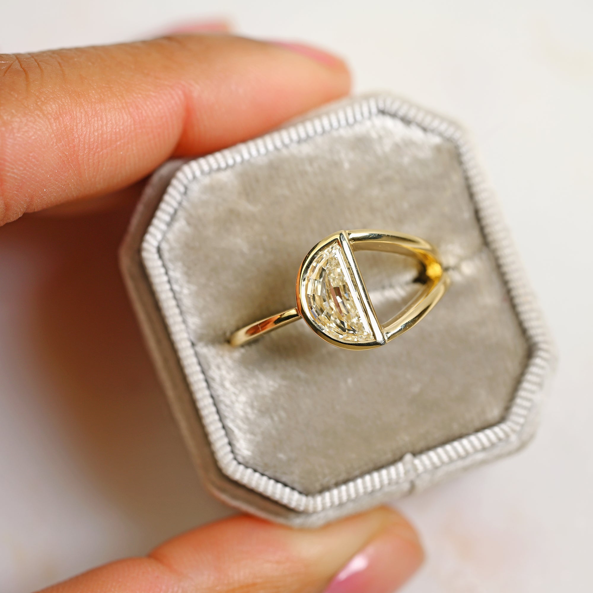 Half moon diamond in a split shank 14k yellow gold engagement ring setting in a gray ring box