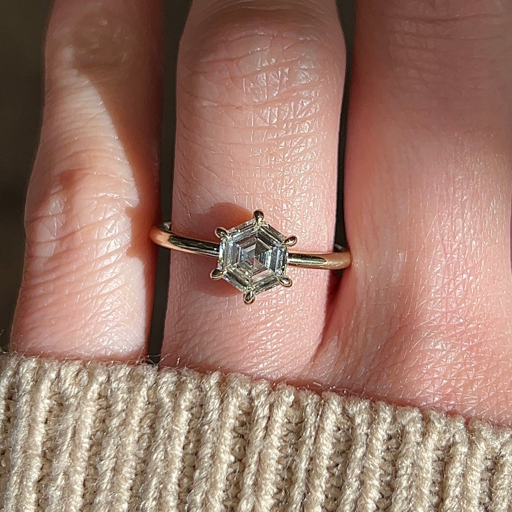 Video of modern hexagon diamond engagement ring in 14k yellow gold solitaire setting with six prongs on a hand
