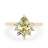 Light green pear shaped sapphire engagement ring with a 14k yellow gold diamond half halo setting