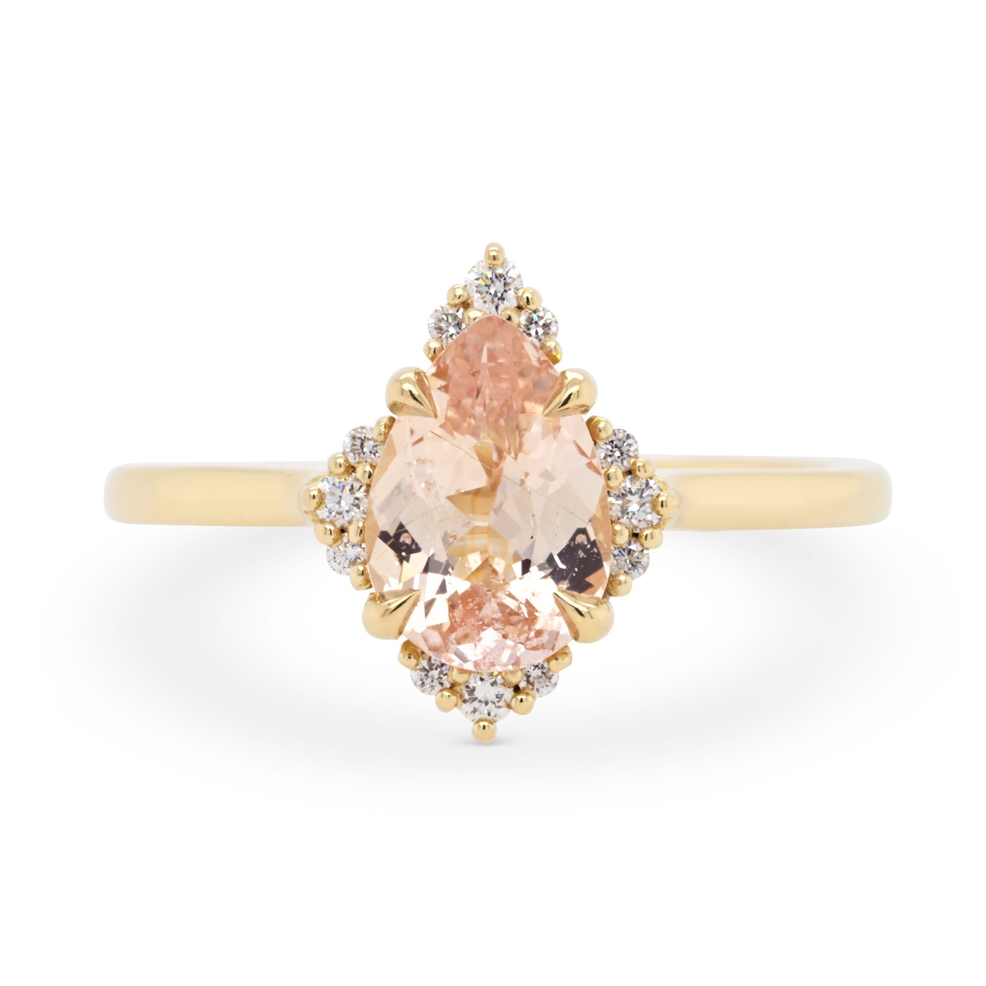 Peach colored pear shaped sapphire engagement ring with a 14k yellow gold diamond halo setting