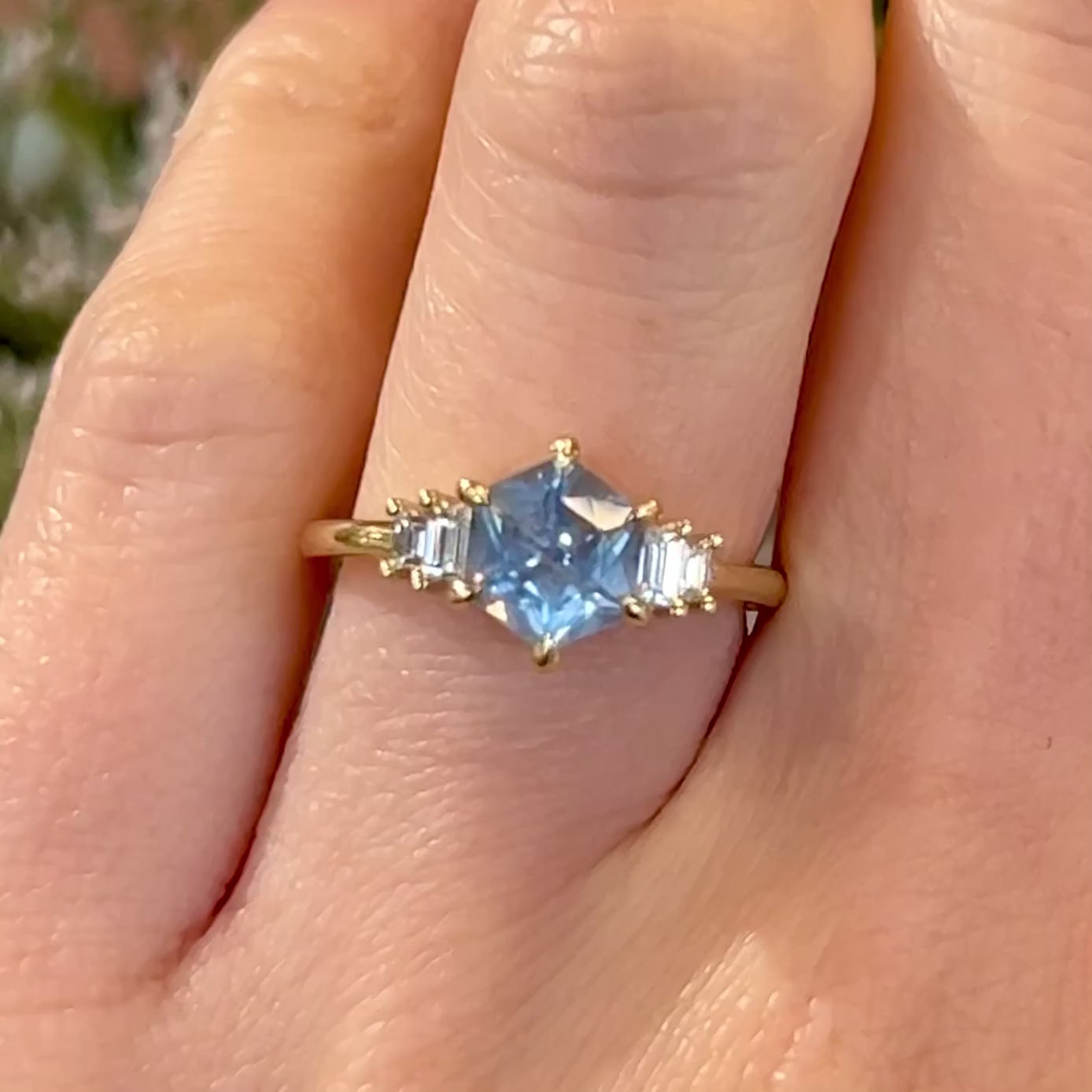 Video of Light blue Montana hexagon sapphire engagement ring with baguette diamonds set in 14k yellow gold on a hand
