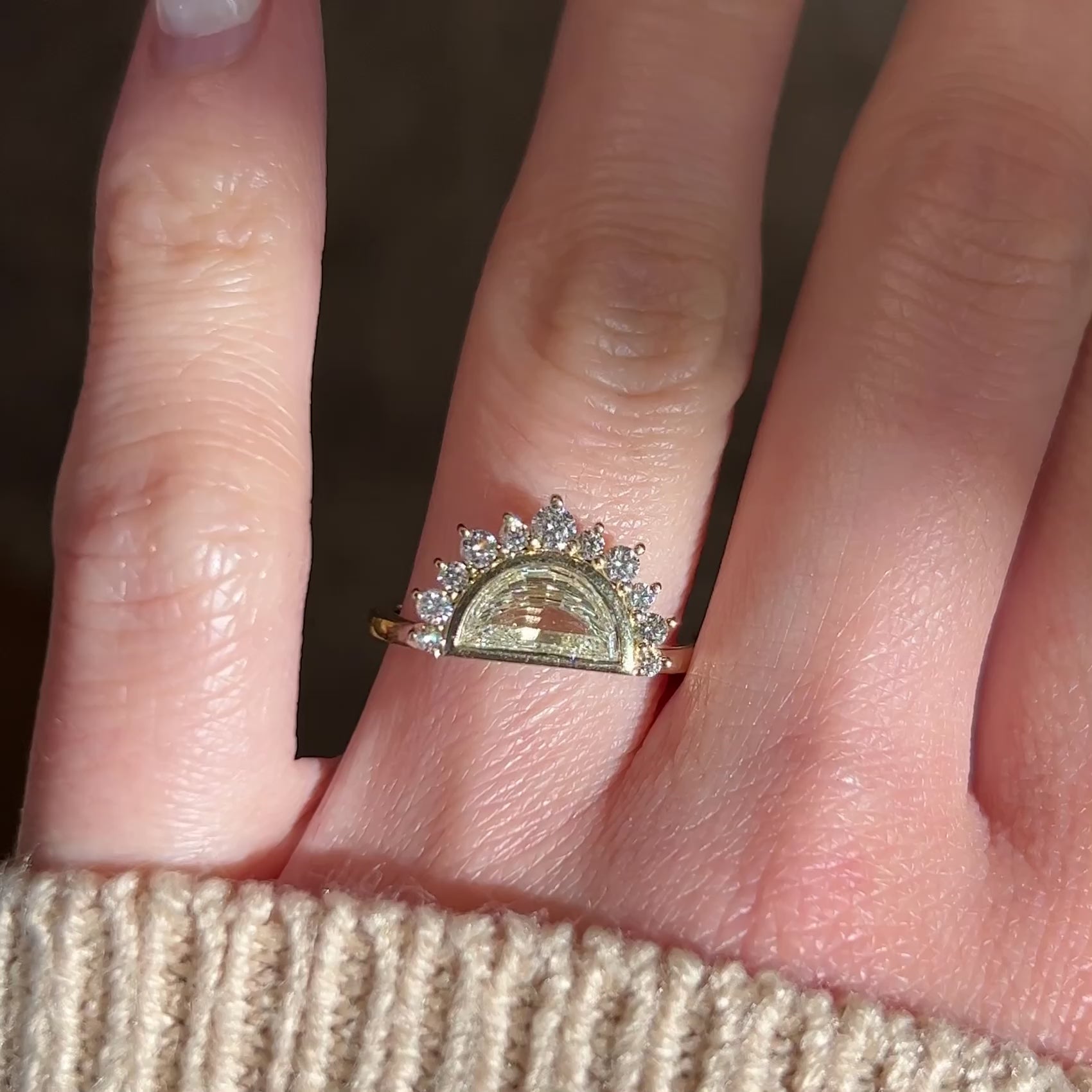 Video of a Half moon diamond engagement ring in a unique 14k yellow gold halo setting on a hand