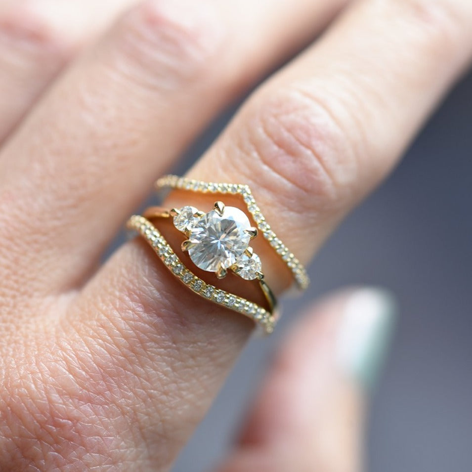 Zara Three Stone Moissanite Engagement Ring On hand with diamond nova band and diamond wave band in yellow 14K gold